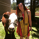 A graduate posing for photo with a cow