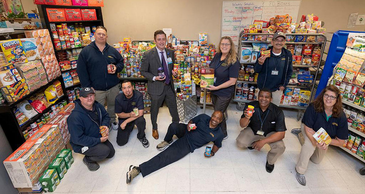 Mail Services personnel pose in front of donated food.