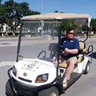 Dan Hawkins driving a golf cart.