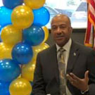 Chancellor May, seated, surrounded by blue and gold balloons.