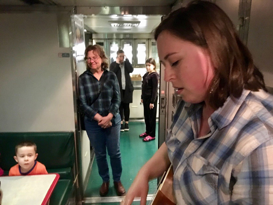 Woman plays ukelele on train.