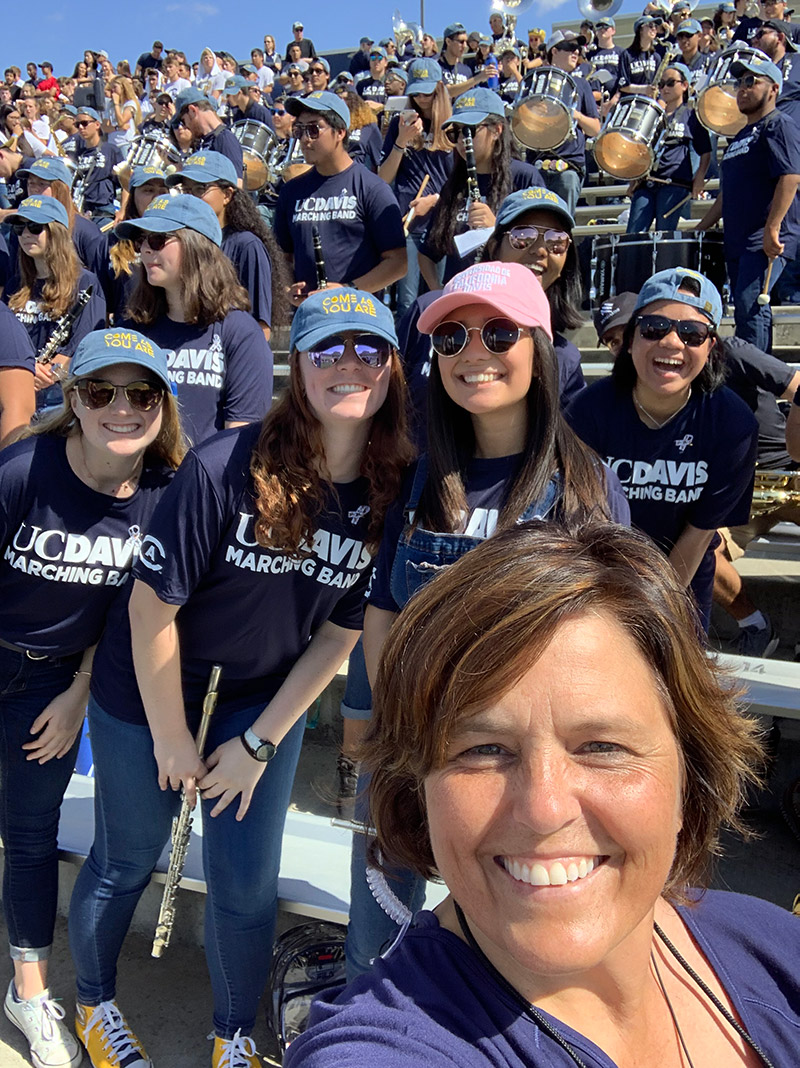 Deb Johnson poses for a selfie with members of the UC Davis Maching Band.