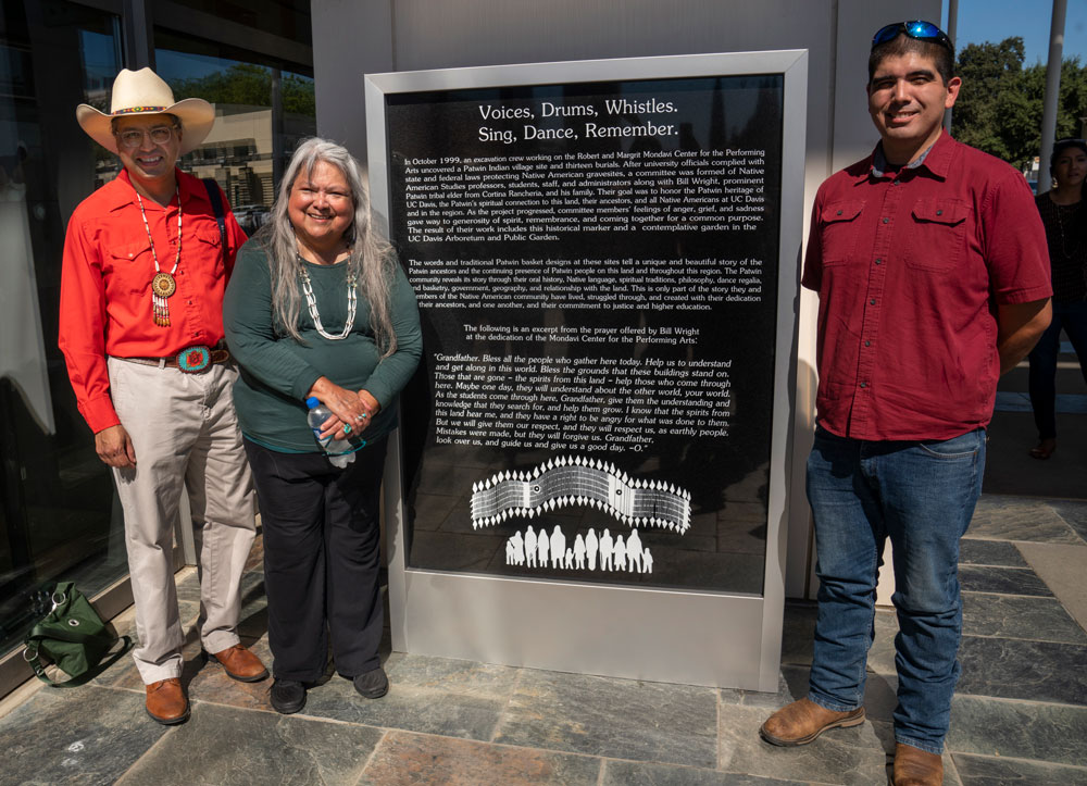 Three people pose with historical marker.