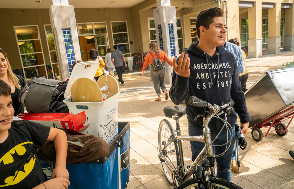 Student gestures with hands in front of his residence hall.