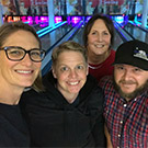 Four people pose for a selfie at a bowling alley.