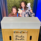Two people pose for a photo in a photo booth.