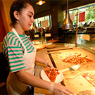 A student worker serves pizza at the CoHo.