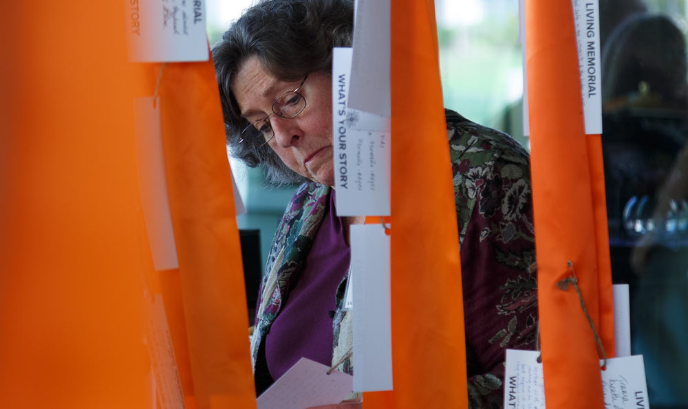 Woman reads tags on orange ribbons.