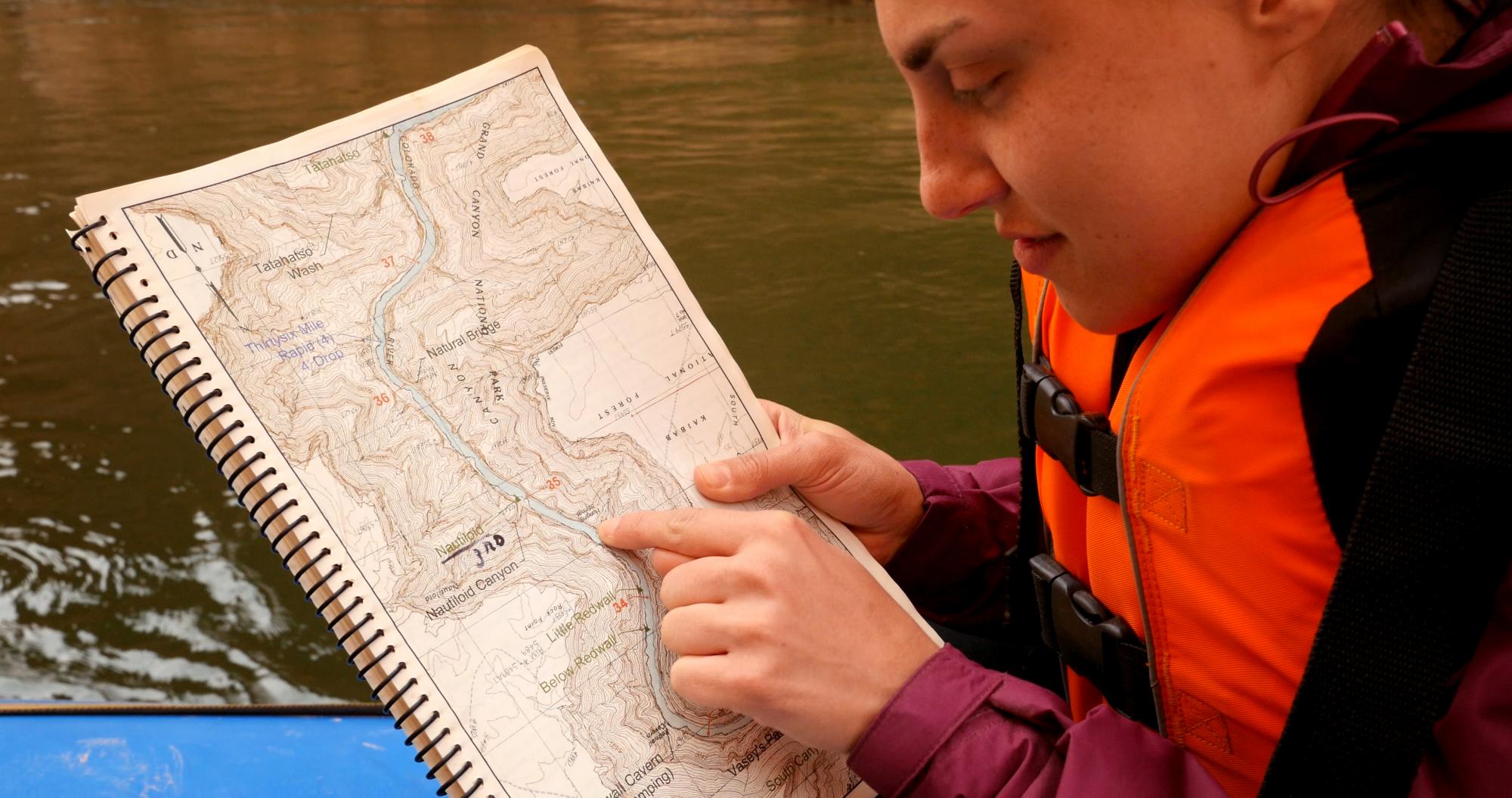 Woman looks at map of Colorado River while on a river raft
