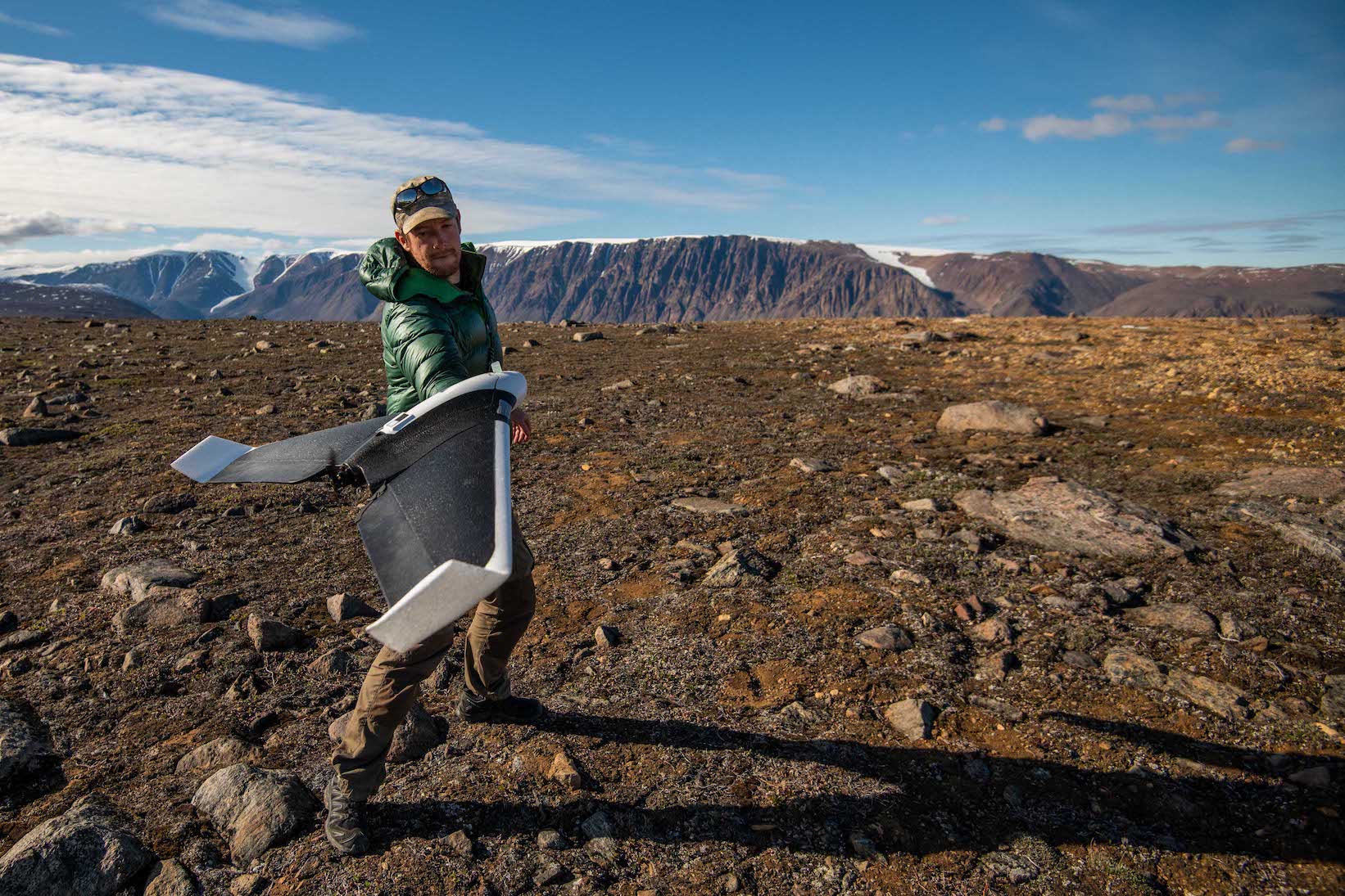 male scientist flies drone in arctic landscape