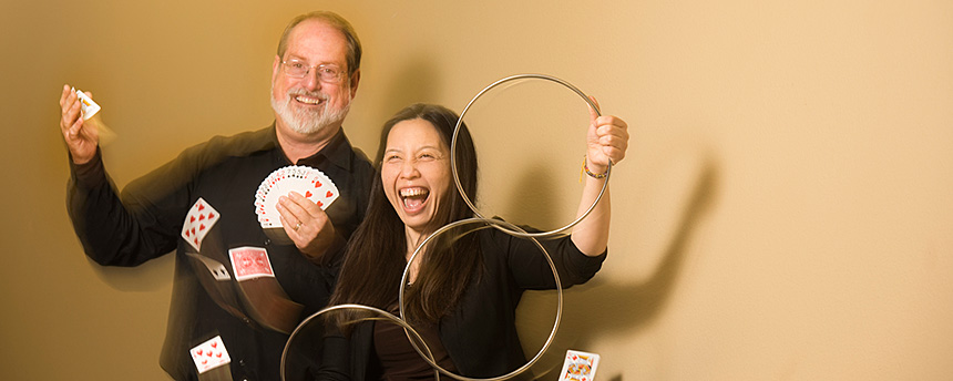 A man with cards flying in the air and a woman with three magic rings, both having a lot of fun