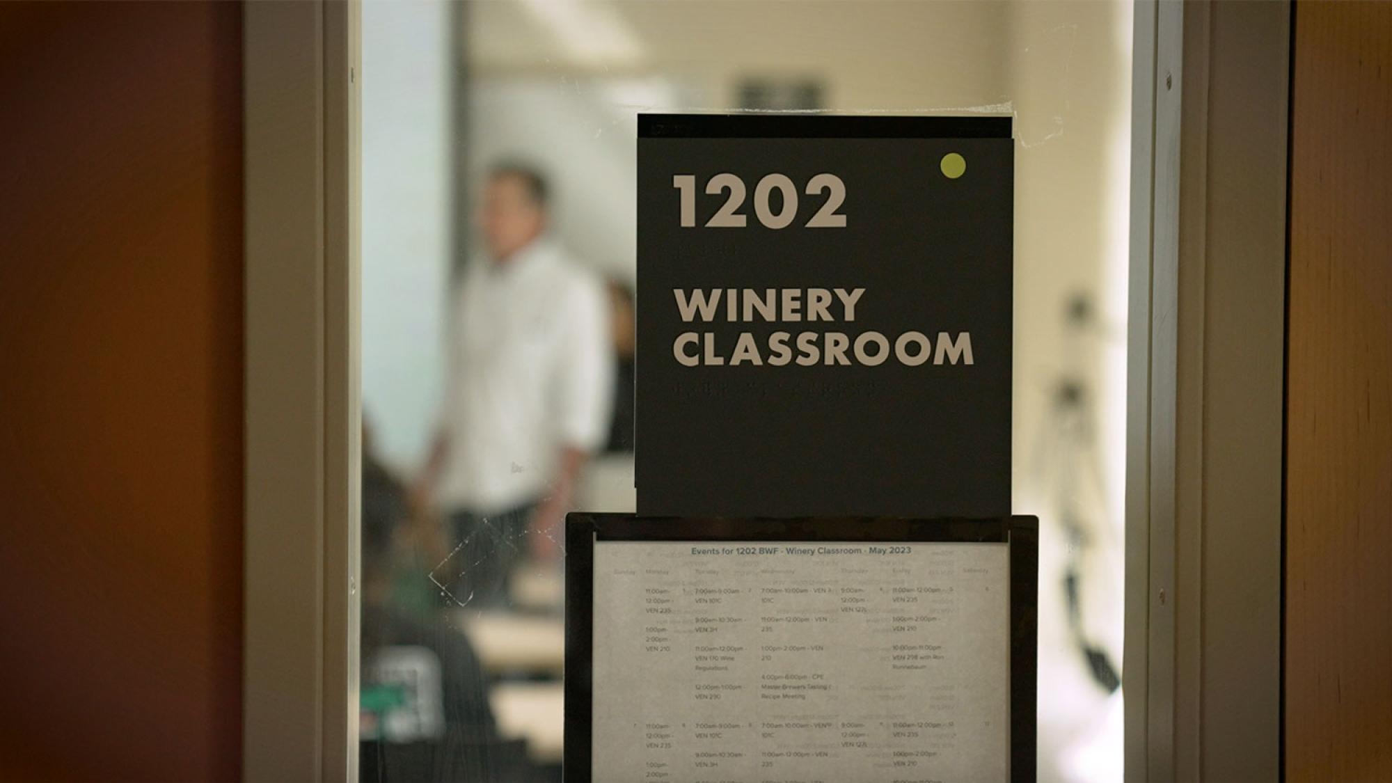 Close shot of a classroom door. The sign reads: "1202 Winery Classroom."