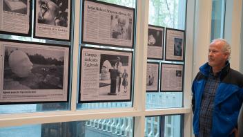 Robert Arneson’s son, Kirk Arneson, stands in front of a collection of newspaper clippings discussing Arneson’s life and works.