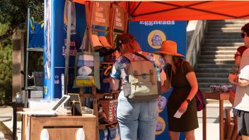 Two women peruse the goods at the outdoors Manetti Shrem Museum Collection Pop-Up Shop on Picnic Day.