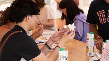 A student shows off his clay Egghead to a friend at a Manetti Shrem Picnic Day event.