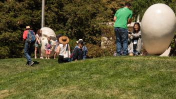 Friends and families stand in front of the See No Evil/Hear No Evil Eggheads on Picnic Day.