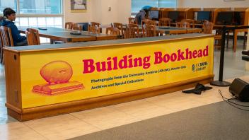 A yellow sign promoting the “Building Bookhead” archive collection is displayed on the front of a long counter in Shields Library.