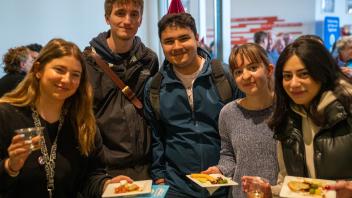 Five students smile happily at the camera with food in their hands at the Year of the Eggheads VIP celebration.