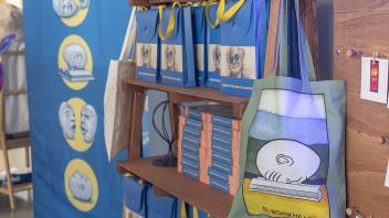 A green “El Bookhead” lotería tote bag sits on display among bags of totes and boxes of scarves at the Manetti Shrem Museum Collection Pop-Up Shop.