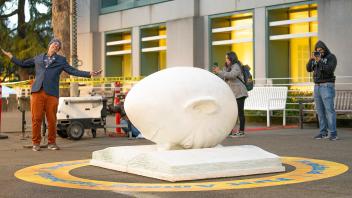 A Strategic Communications staff member stands with his arms outstretched while Bookhead is lit for the Year of the Eggheads VIP celebration.