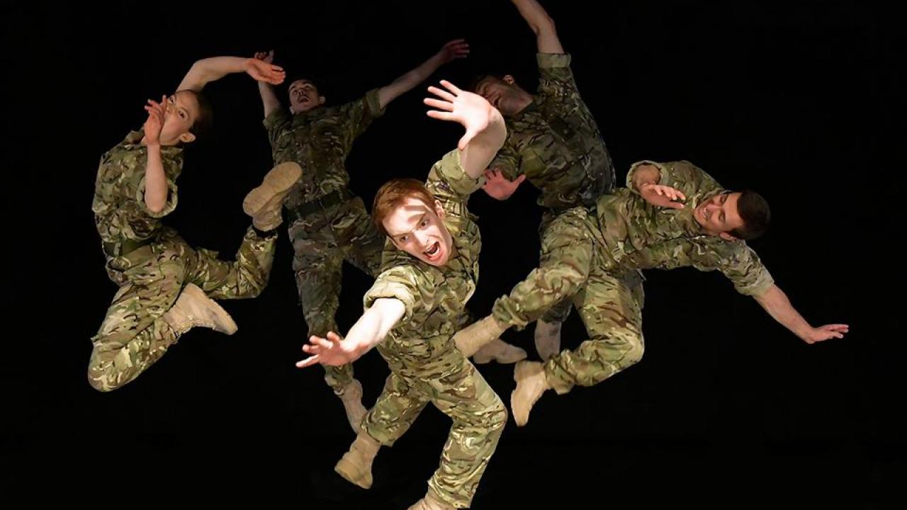 Five dancers dressed in army camouflage caught in various positions suepended in the air.