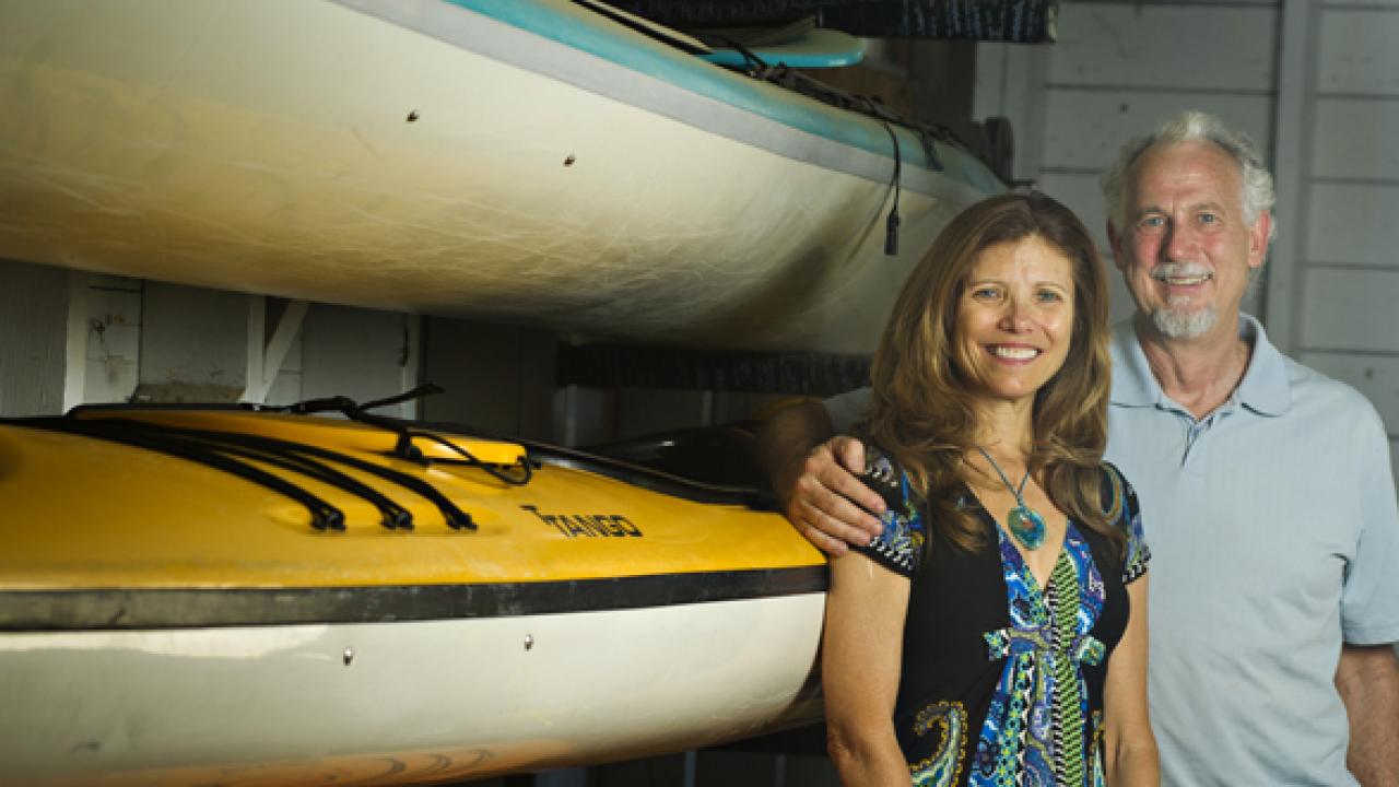 Photo: Sharon Coulson and Ted Abresch, husband and wife, in front of ocean kayaks at Outdoor Adventures
