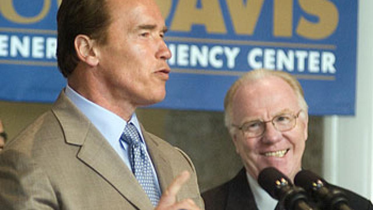 Photo: Gov. Schwarzenegger speaking at microphone with man looking on from right.