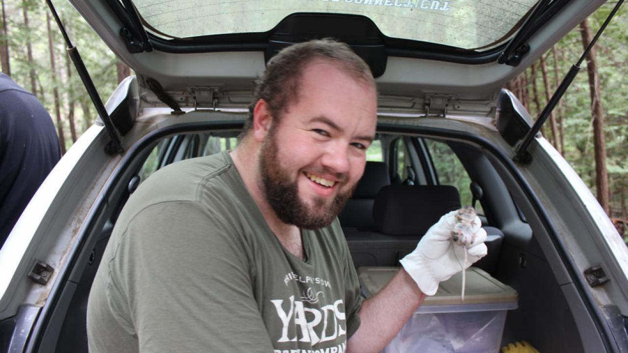 Ben Plourde, seated in back of SUV, holds deer mouse.