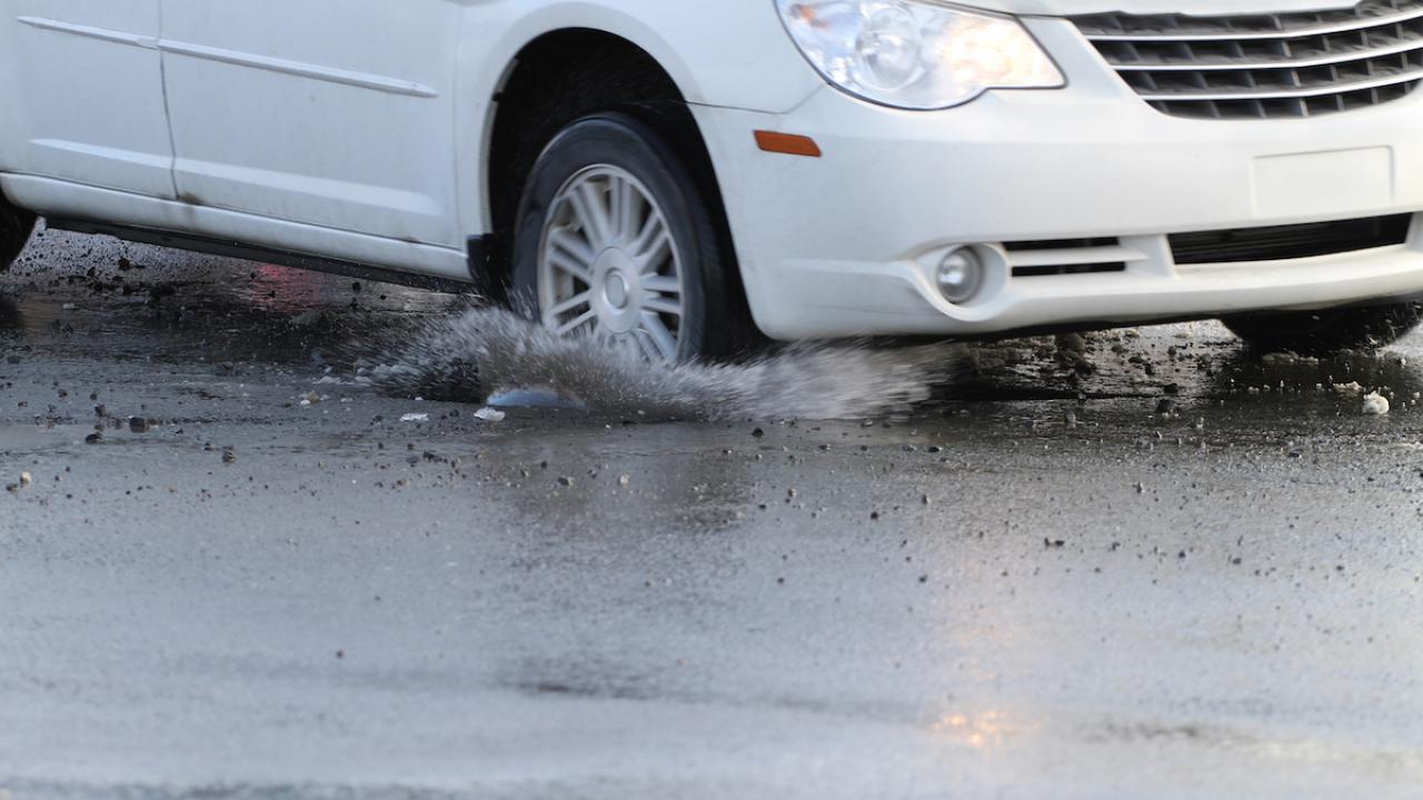 Car splashes tire in pothole