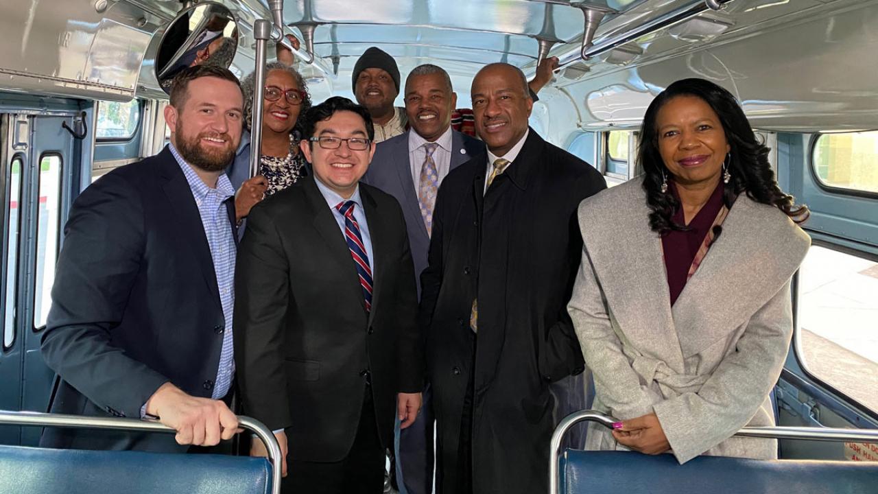 Chancellor Gary S. May amid group of people on historic bus