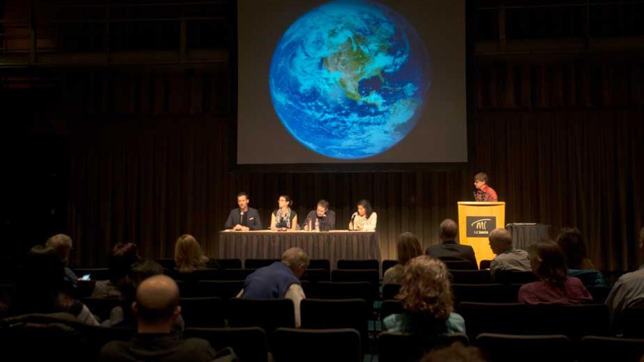 Roundtable panelists under slide of the earth.
