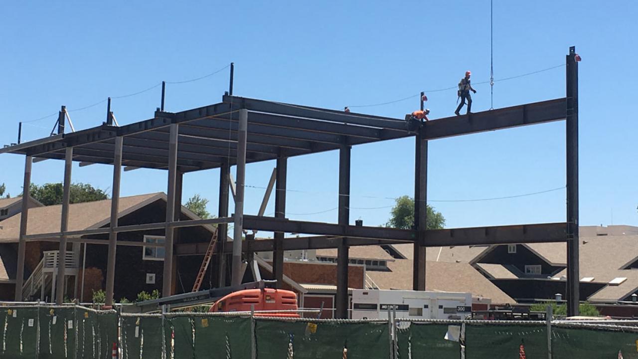 Construction worker walks along steel beam.