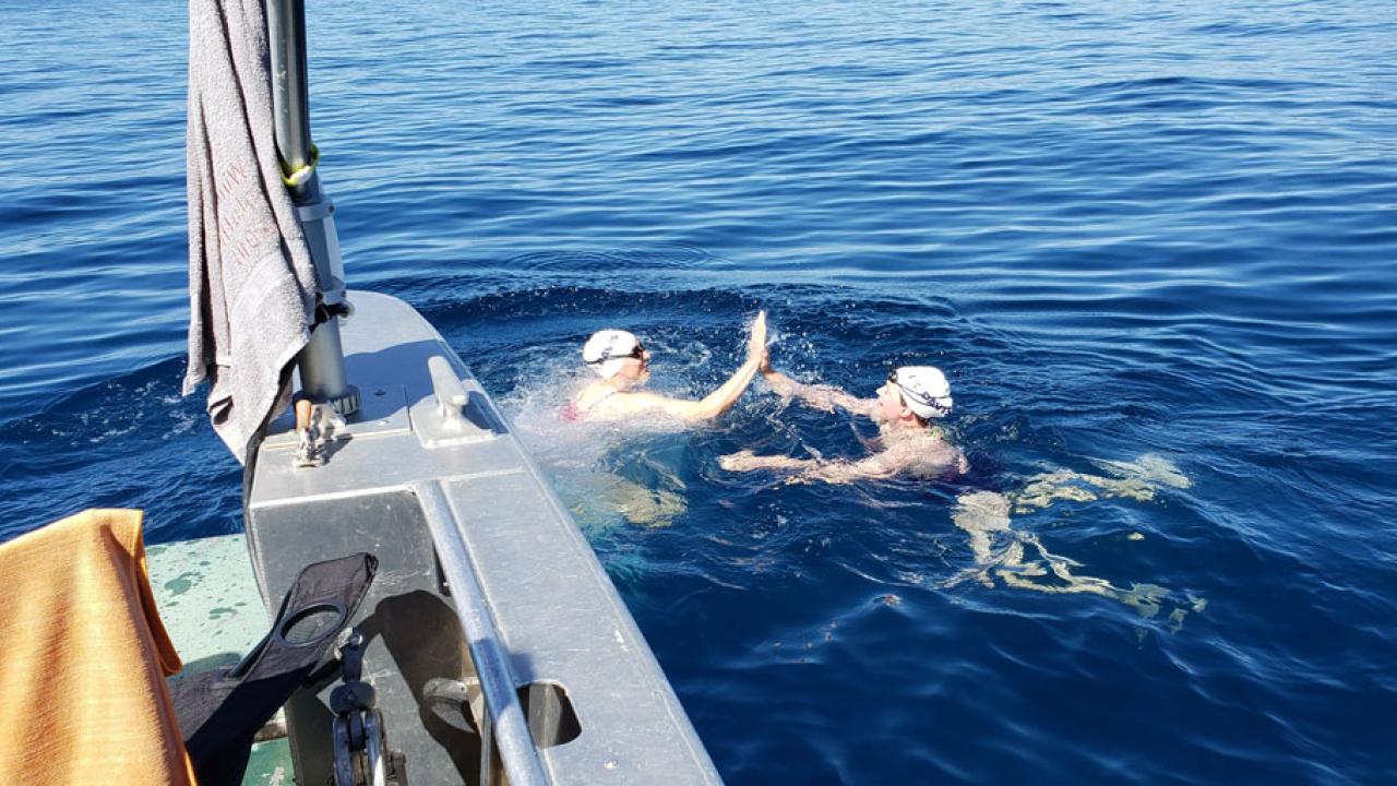 Two swimmers touch handsw together in Lake Tahoe.