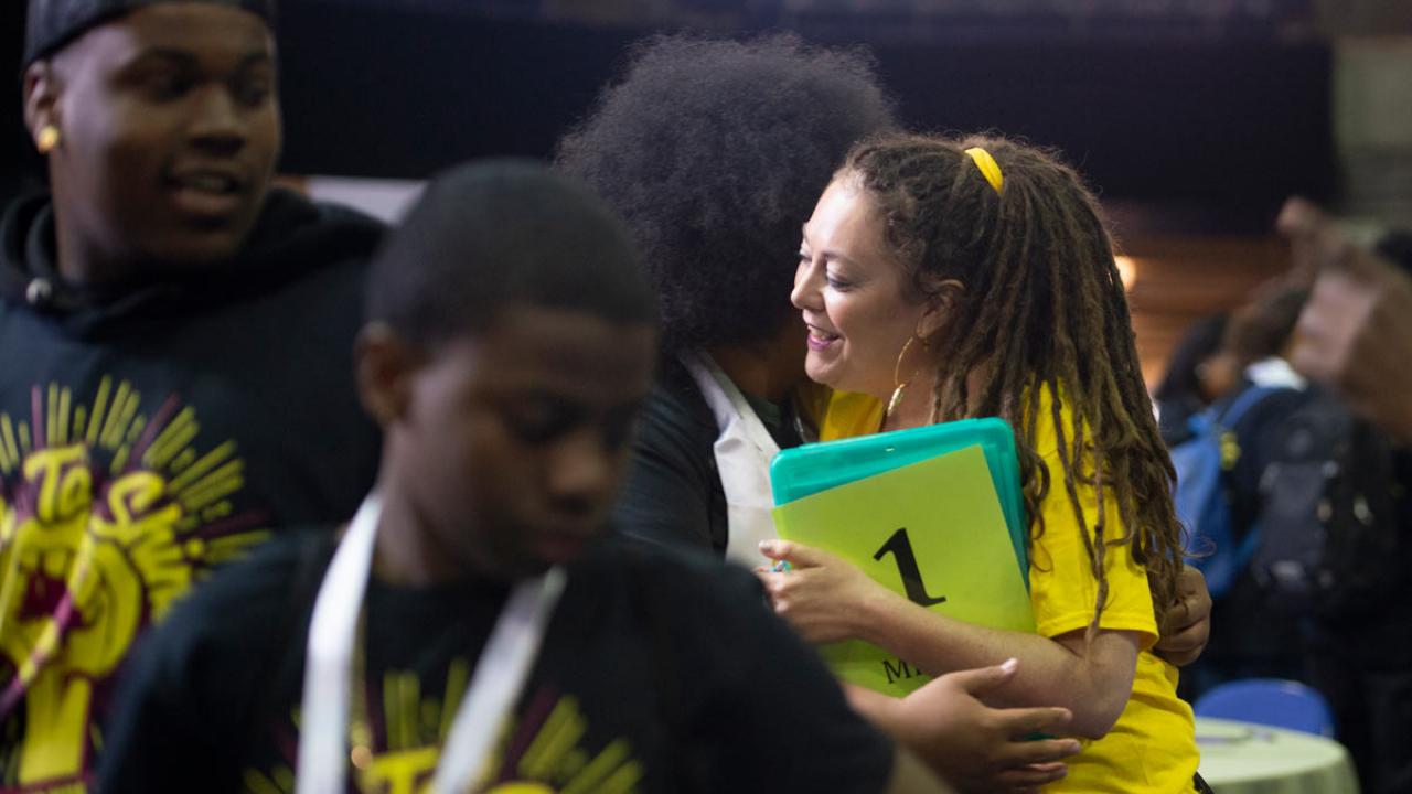 Woman hugs student participant at conference.