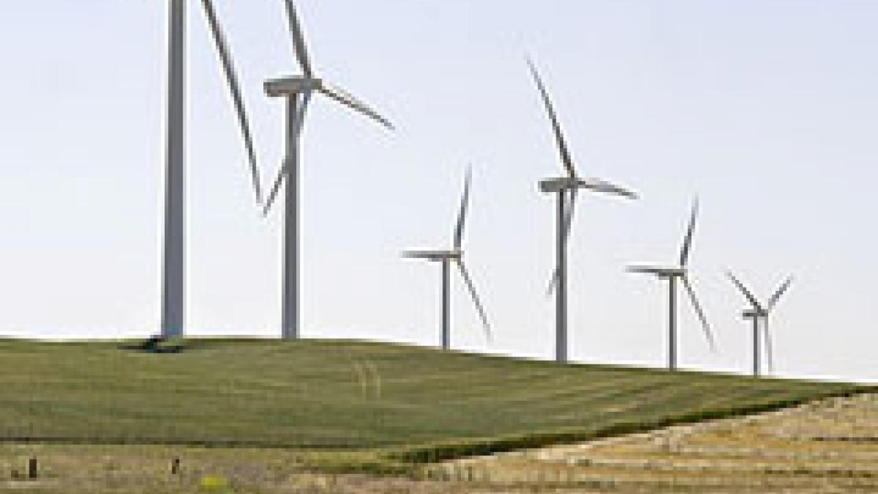Photo: Wind turbines on a hill with a rural fence in foreground