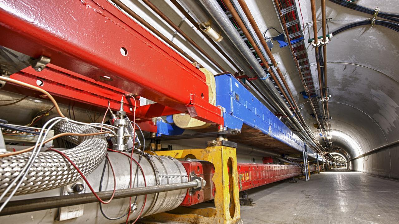 Large red and blue machines in a long tunnel curving to the right.