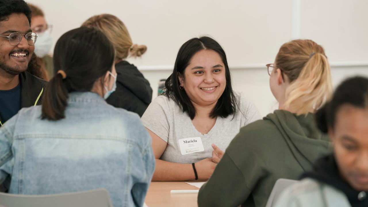 Students smile while sitting around a desk during a UC Davis Teaching Assistant Conference at the Teaching Learning Complex on September 19, 2022.