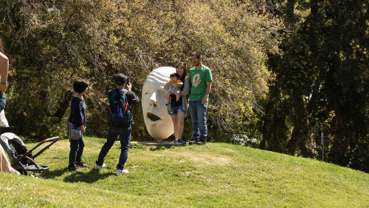 An Aggie family poses with one half of the popular Egghead duo "Hear No Evil/See No Evil" in front of King Hall.