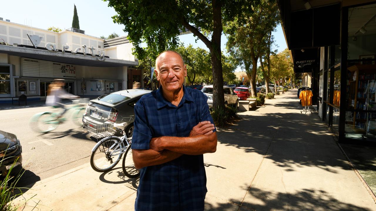 Man stands on street with arms folded in front