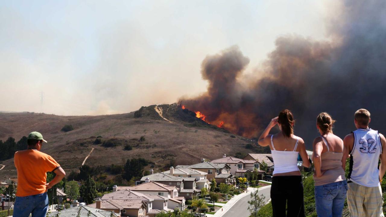 People watch a fire approaching homes