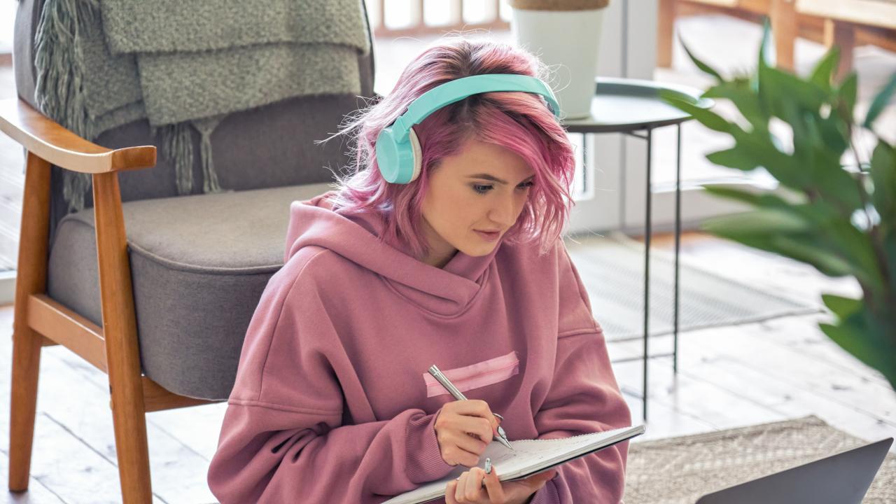 Young woman with pink hair and pink shirt, wearing headphones