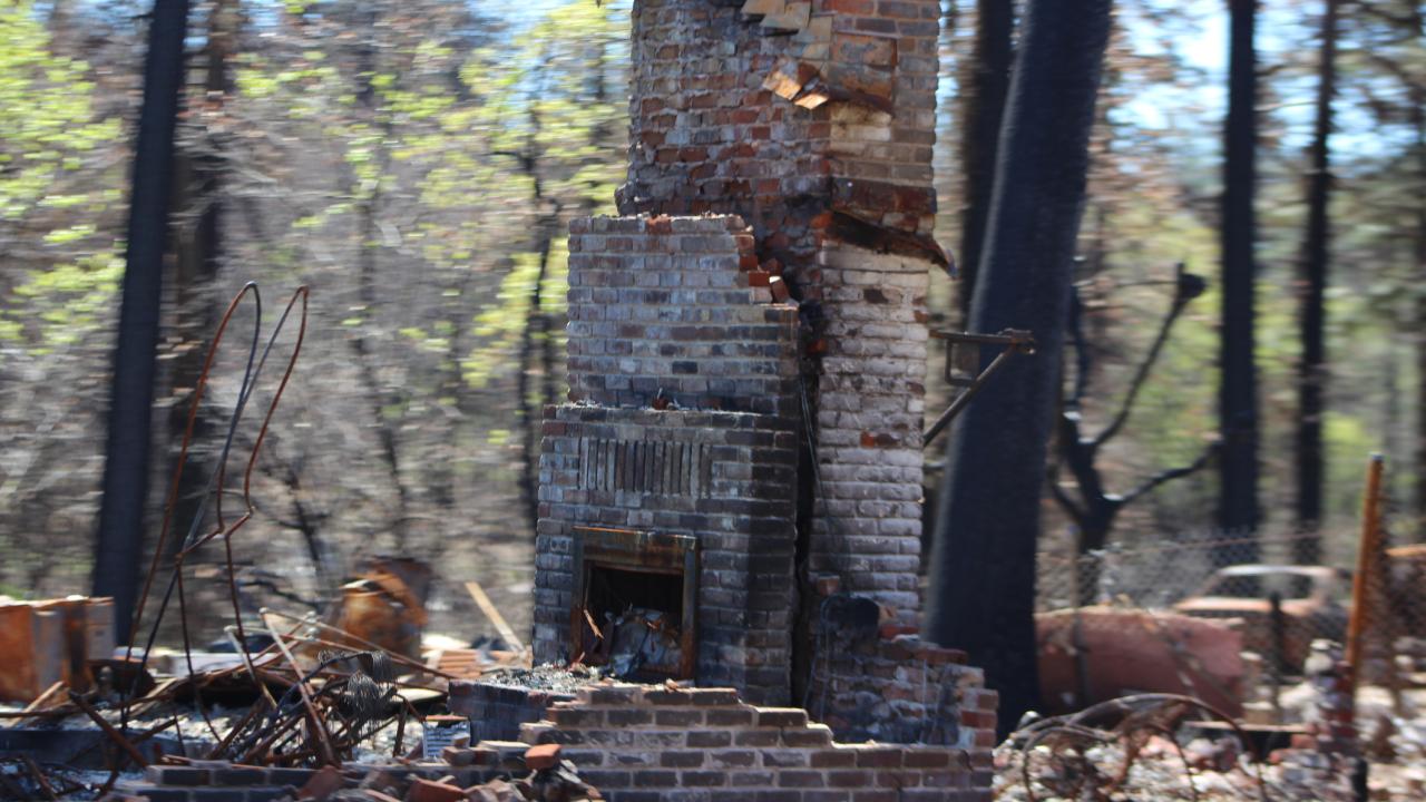 A brick fireplace standing amidst rubble from a burnt down house.