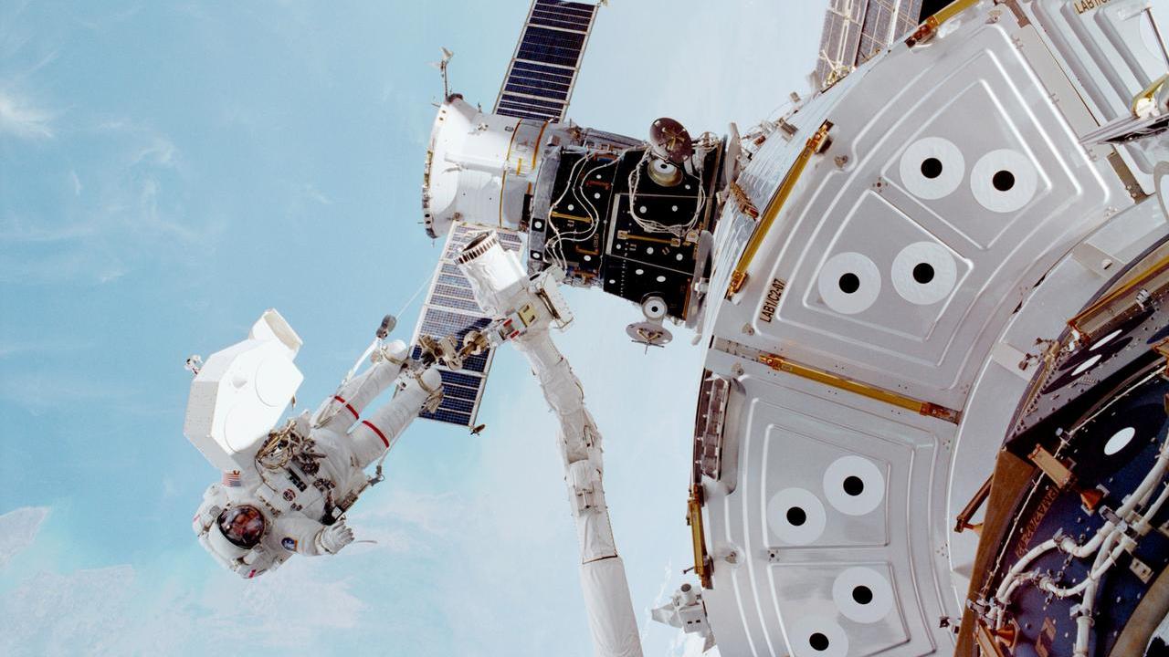 An astronaut making a spacewalk outside a space station. 