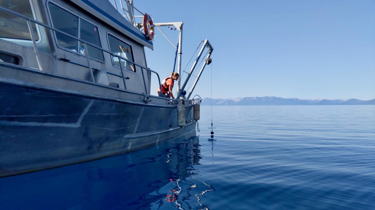Female scientist lowers a Secchi disk from a research boat into Lake Tahoe to measure lake clarity.