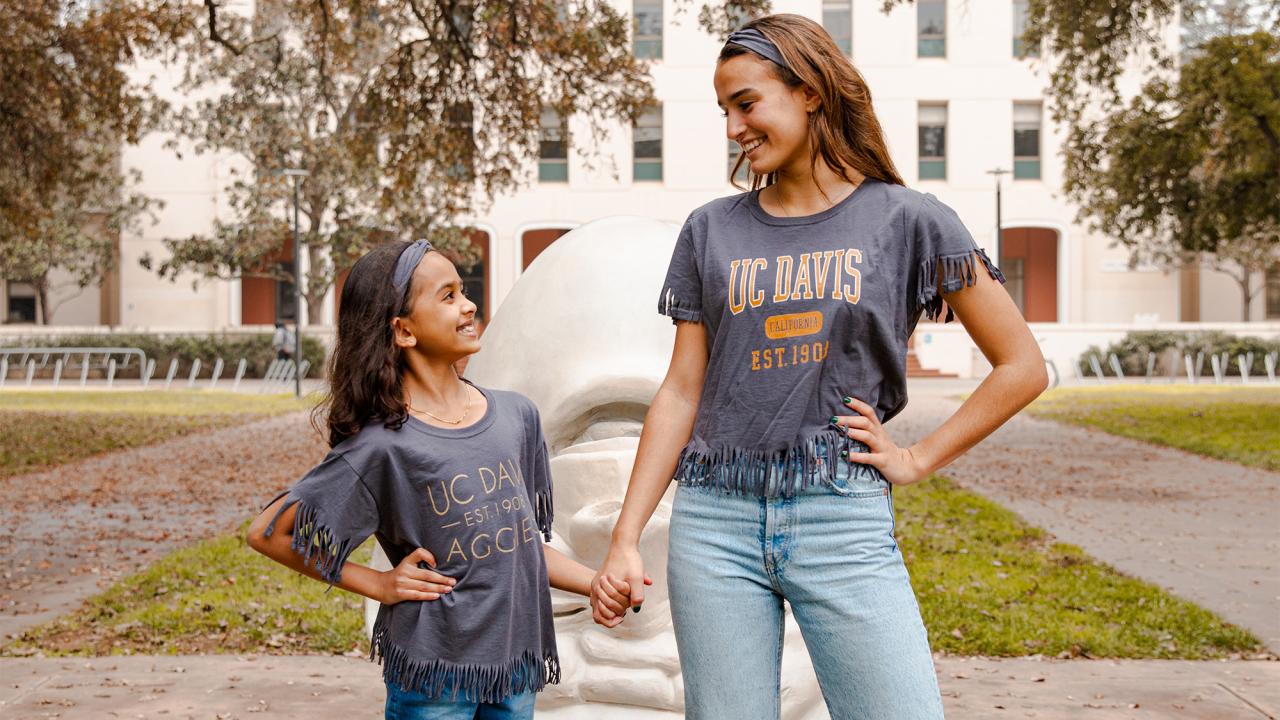 Young girl and teen pose for photo next to UC Davis Egghead sculpture.