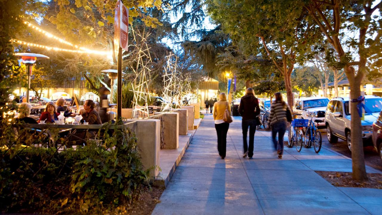 A view of downtown davis during the evening with shoppers and restaurant patrons enjoying the atmosphere