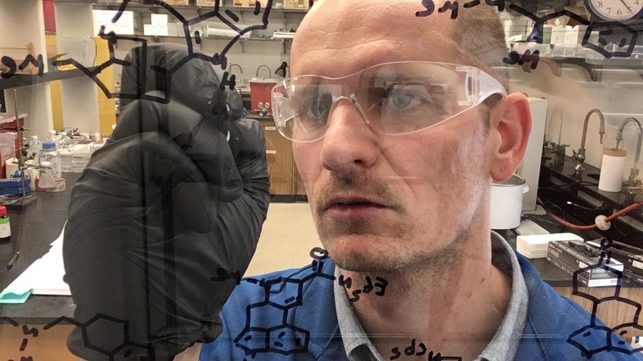 Man writes chemical formula on clear board