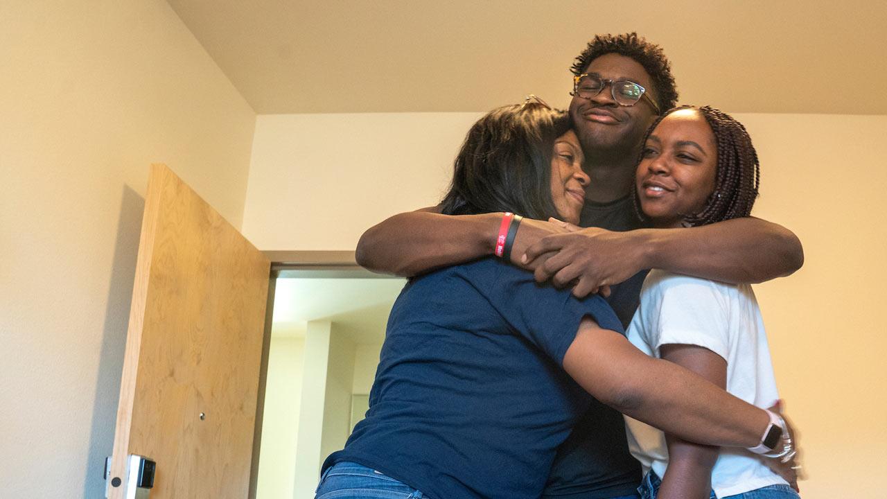 A new freshman student hugs his sister and his mother in his new dorm room on UC Davis move in day.