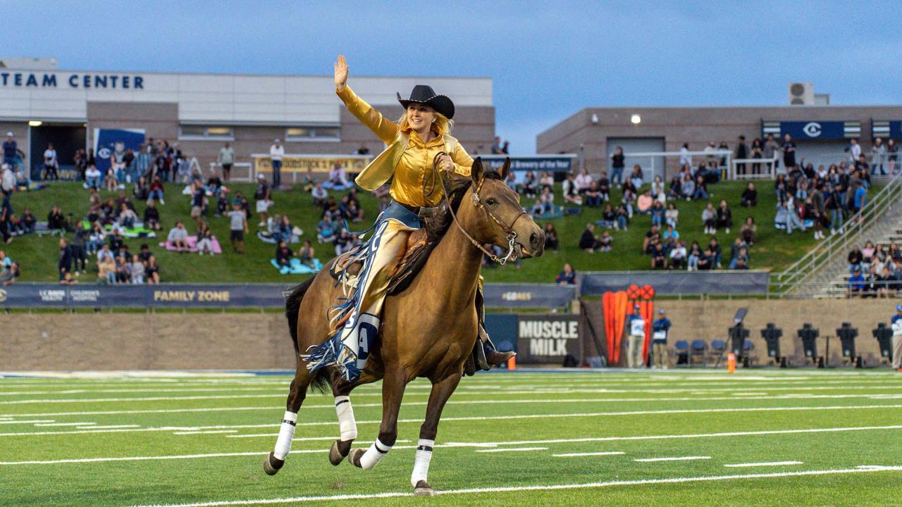 Student rides horse onto football field.