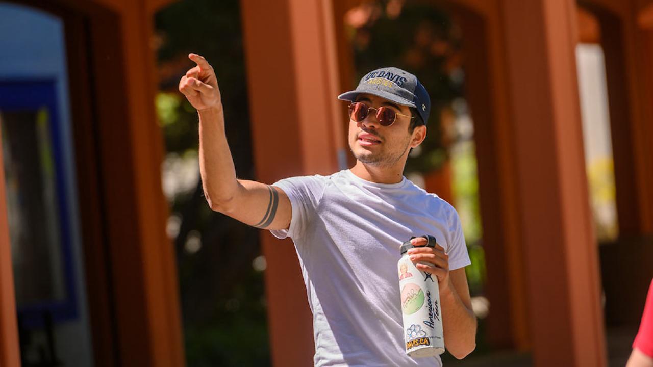 male tour guide pointing out a UC Davis campus landmark